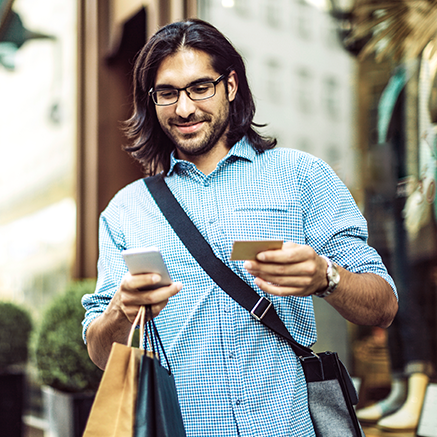 Debit Mastercard® Overdraft Service man walking with shopping bags on mobile phone
