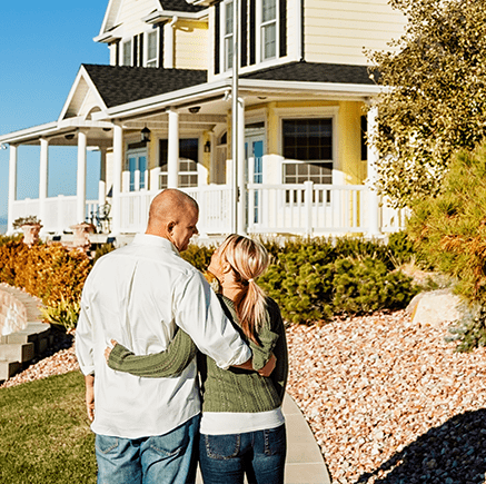 Benefits couple standing in front of new home