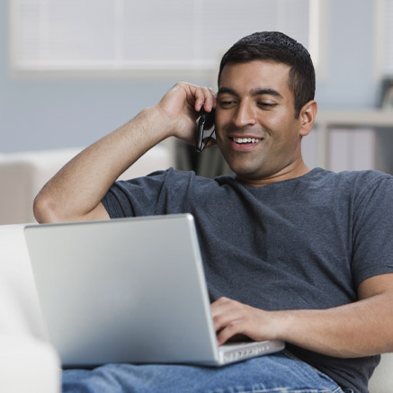 Over the Phone man talking on the phone and looking at laptop
