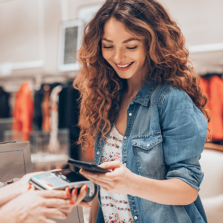 The Basics woman paying at counter with mobile phone